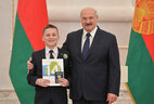 Belarus President Aleksandr Lukashenko presents a passport to student of Oshmyany gymnasium No. 1 Yegor Savanets