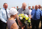 Alexander Lukashenko presents flowers to harvester operator Irina Khoruzhaya