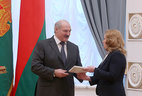 Alexander Lukashenko presents Natalia Karpovich with an identity document of the judge of the Constitutional Court as well as a gift-wrapped copy of the Constitution